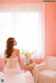 A woman sitting on a bed in front of a window.