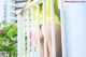 A woman in a yellow shirt is standing on a balcony.