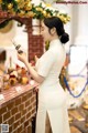 A woman in a white dress standing in front of a counter.