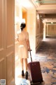 A woman walking down a hallway with a suitcase.