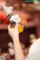 A person holding a small stuffed animal in a glass jar.