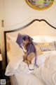 A woman laying on a bed holding a purple bra.