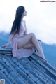 A woman sitting on top of a roof with her legs crossed.