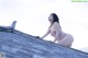 A woman in a pink bathing suit leaning on a roof.