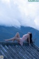 A woman in a pink dress laying on a roof.