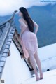 A woman in a pink dress standing on a roof.