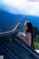 A woman in a pink bikini leaning on a roof.