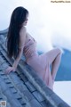 A woman in a pink dress sitting on a roof.