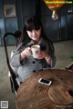 A woman sitting at a table holding a cup of coffee.