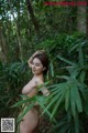 A naked woman standing in the middle of a forest.