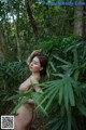 A naked woman standing in the middle of a forest.