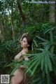 A naked woman standing in the middle of a forest.