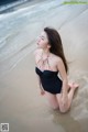 A woman in a black bathing suit sitting in the water.