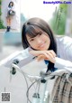 A young woman leaning on a bike with her hand on the handlebars.