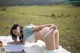 A woman laying on a blanket in a field.