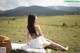 A woman sitting on a blanket in a field.