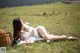 A woman laying on the grass with a basket of flowers.