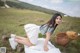 A woman in a white dress sitting on a blanket in a field.