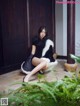 A woman in a black dress sitting on the ground.