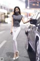 A woman wearing a face mask standing next to a car.