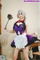 A woman dressed in a maid outfit holding a broom.