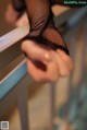 A woman in fishnet stockings holding onto a railing.