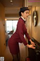 A woman in a red uniform is putting on a suitcase.