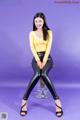 A woman sitting on top of a stool wearing black leather pants.