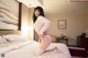 A woman in a white sweater and pink panties on a bed.