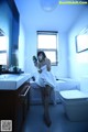 A woman in a white towel standing in a bathroom.