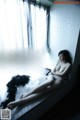 A naked woman sitting on a window sill next to a window.