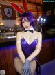 A woman in a bunny costume sitting at a bar.