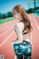 A woman in a sports bra top and leggings standing on a track.