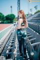 A woman in a sports bra top and leggings standing in a stadium.