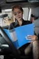 A woman sitting in the back seat of a car reading a book.