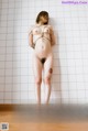 A naked woman is tied up in a bathroom.