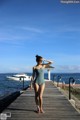 A woman in a blue swimsuit standing on a wooden pier.