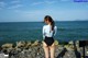 A woman standing on a rocky beach next to the ocean.