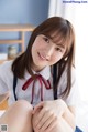 A young woman in a school uniform sitting on a bed.