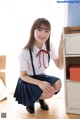 A young woman in a school uniform crouching on the floor.