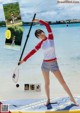 A woman standing on a paddle board on the beach.