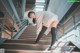 A woman in a white sweater and black tights is walking up some stairs.