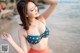 A woman in a blue and orange polka dot bikini on the beach.