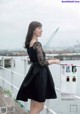 A woman in a black dress standing on a pier.