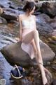 A woman sitting on a rock in the water.