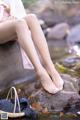 A woman sitting on a rock next to a stream.