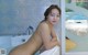 A naked woman sitting in a bathtub in a bathroom.