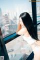 A woman with long black hair standing in front of a window.