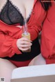 A woman in a red shirt holding a bottle of beer.