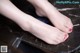 A woman's feet with red nail polish on a marble table.